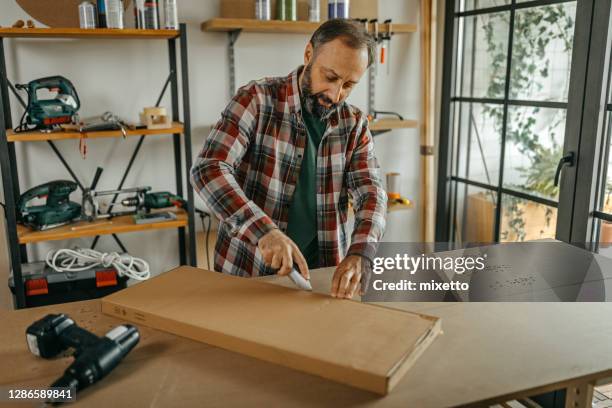 man opening cardboard package with scalpel at home - craft knife stock pictures, royalty-free photos & images