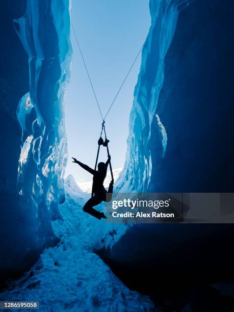 silhouette of a acrobat performing in a deep blue ice cave inside of a glacier - crevasse stock pictures, royalty-free photos & images