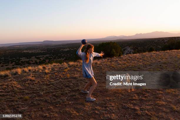 teenage girl throwing football at sunset. - desert dog stockfoto's en -beelden