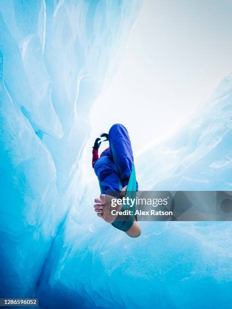 low angle shot looking strait up at a aerial acrobat performing in a deep glacier crevasse in the bottom of a glacier - adult gymnast feet stock-fotos und bilder