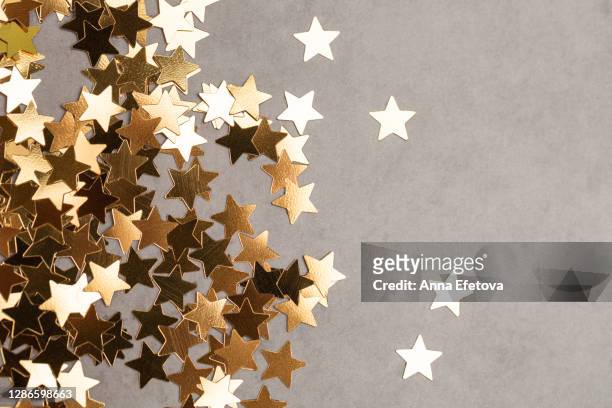 star shaped confetti on gray background. illuminating new year backdrop. - congratulating stock pictures, royalty-free photos & images