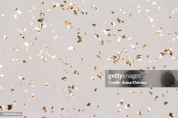 shiny golden confetti falling down. illuminating new year backdrop. - gold confetti stock-fotos und bilder