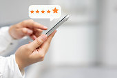 close up on customer woman hand pressing on smartphone screen with  five star rating feedback icon and press level excellent rank for giving best score point to review the service , technology business concept