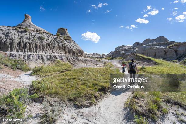 mother and son hiking in badlands of dinosaur provincial park in alberta, canada - alberta badlands stock pictures, royalty-free photos & images