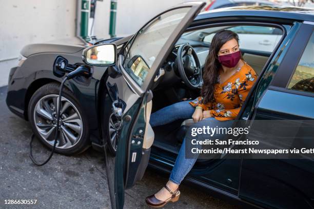 Portrait of Maya Katz-Ali with her new car charging at a station along Lakeshore Avenue, Tuesday, Nov. 10 in Oakland, Calif. Katz-Ali recently bought...