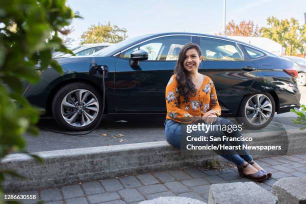 Portrait of Maya Katz-Ali with her new car charging at a station along Lakeshore Avenue, Tuesday, Nov. 10 in Oakland, Calif. Katz-Ali recently bought...