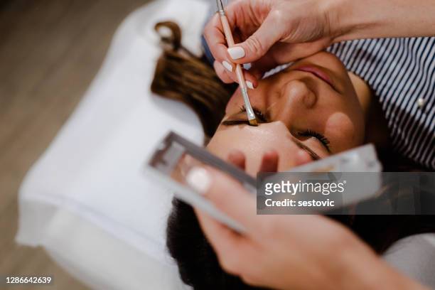 mujer joven en corrección de cejas en clínica de cosmetología - tatuaje de henna fotografías e imágenes de stock