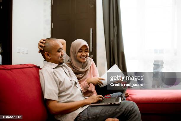 young asian couple using laptop to pay bill at home - islamic finance stock pictures, royalty-free photos & images