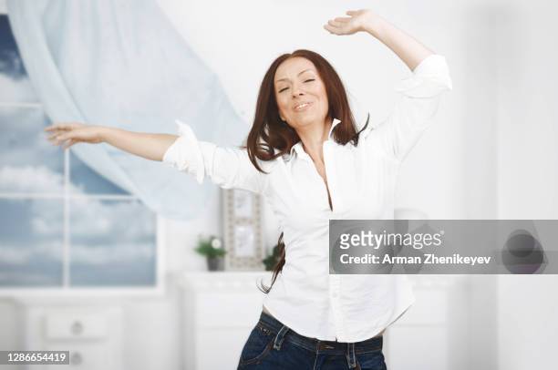 happy woman dancing at home - endast en medelålders kvinna bildbanksfoton och bilder