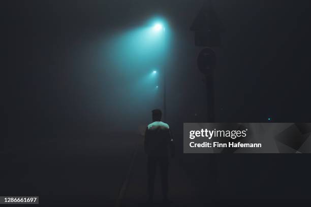 man waiting alone in dark foggy illuminated city street - one night stand stock pictures, royalty-free photos & images