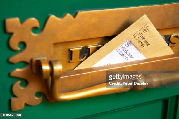 Photograph shows a front door letter box with HMRC envelope, Her Majestys Revenue and Customs reminding of the date that self-assessment tax returns...