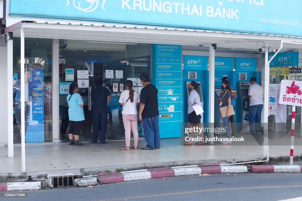 Thai people are standing in queue in front of bank in Bangkok
