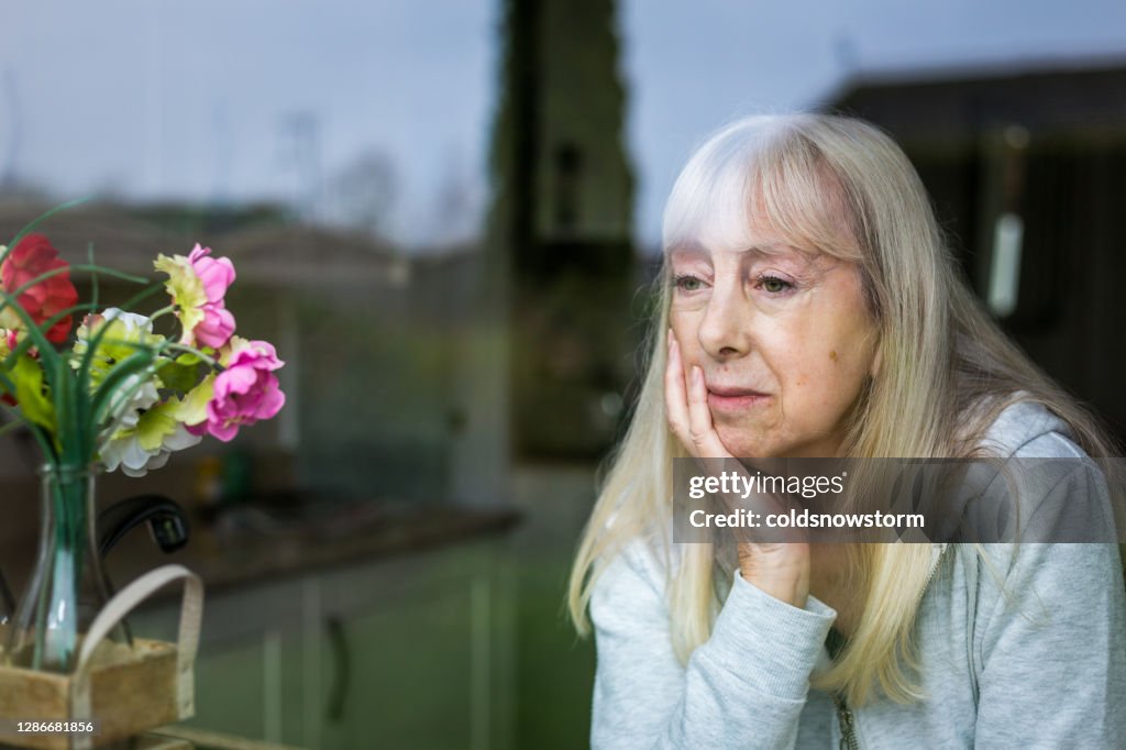 Depressive Seniorin schaut aus dem Fenster