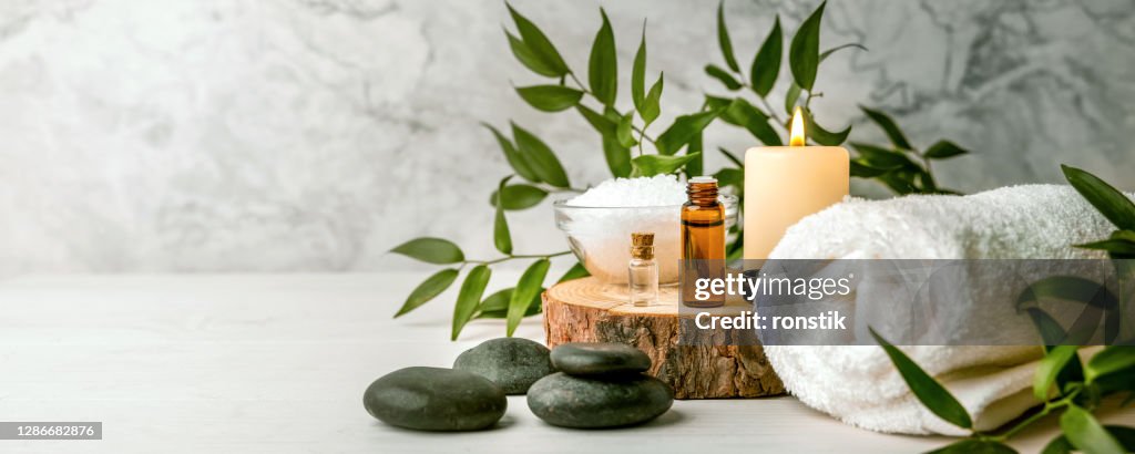 Articoli per trattamenti di bellezza per procedure termali su tavolo in legno bianco. pietre da massaggio, oli essenziali e sale marino. spazio di copia