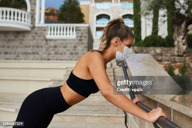 young woman with protective face mask jogging and exercising in the city - form fitted stock pictures, royalty-free photos & images