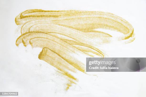 smears of golden glitters on white background - gold dust stock-fotos und bilder