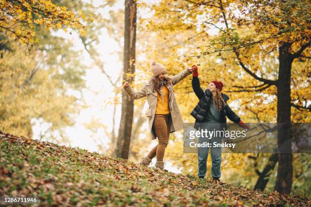 mom and her daughter dancing in forest, enjoying fresh autumn day. - october 28 stock pictures, royalty-free photos & images