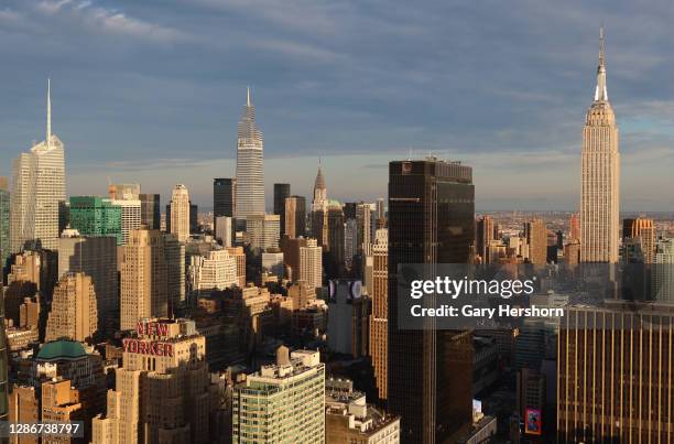 The sun sets on the skyline of midtown Manhattan, the Bank of America Building, One Vanderbilt, the Chrysler Building, One Penn Plaza and the Empire...
