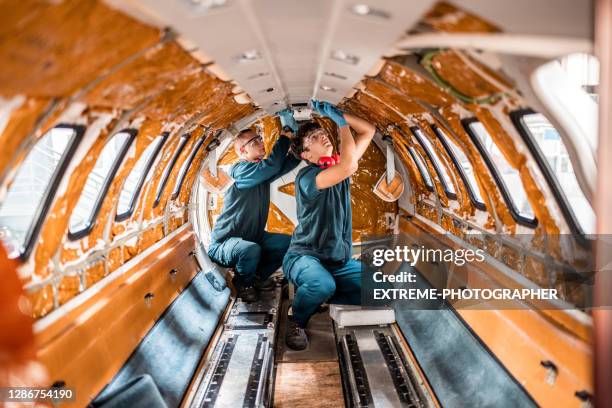 two maintenance mechanics repairing the interior of the jet airplane - aeroplane engineer stock pictures, royalty-free photos & images