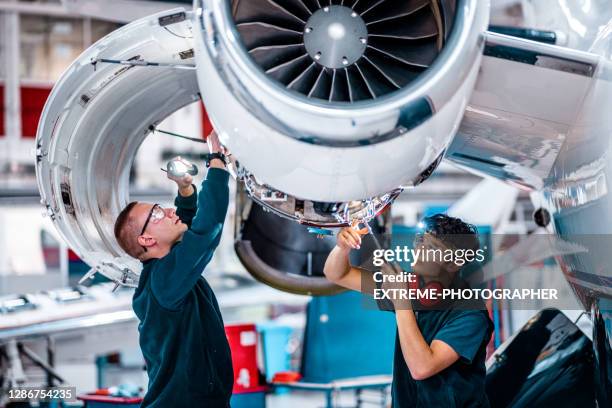 two maintenance engineers inspecting a jet engine - veículo aéreo imagens e fotografias de stock