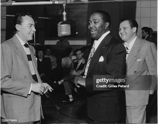 Woody Herman, Louis Jordan and Al Jarvis, by a microphone in a recording studio, USA, 1945.