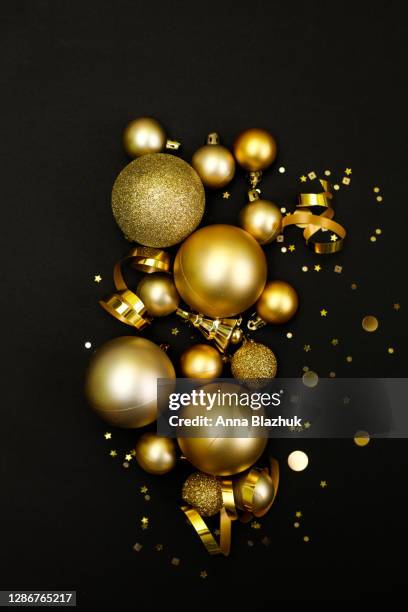 golden christmas and new year baubles. festive decor and confetti over black background. copy space. - boule noel photos et images de collection