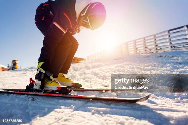 jonge mens die ski's op zet - skischoen stockfoto's en -beelden