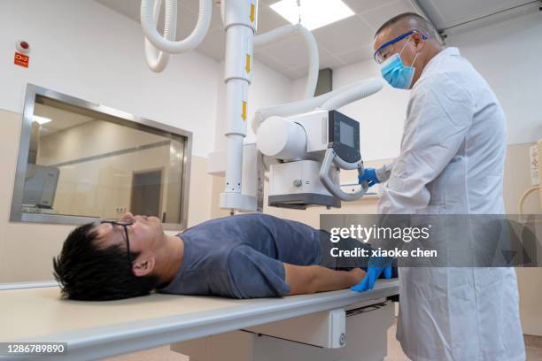 male patient undergoing x-ray examination - medical examination room stock pictures, royalty-free photos & images