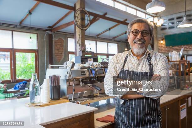 retrato del hombre mayor asiático barista o propietario de café usando cafetera y buscando cámara en el mostrador del bar en la cafetería, concepto de propietario de pequeñas empresas - propietario fotografías e imágenes de stock