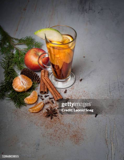 food photography of christmas still life side view with a glass of hot mulled wine with spices and decorations on a gray textured background close up with place for text - apfelpunsch stock-fotos und bilder