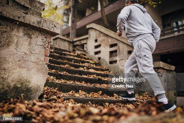 年配の男性が紅葉の階段でエクササイズをする - 階段　のぼる ストックフォトと画像