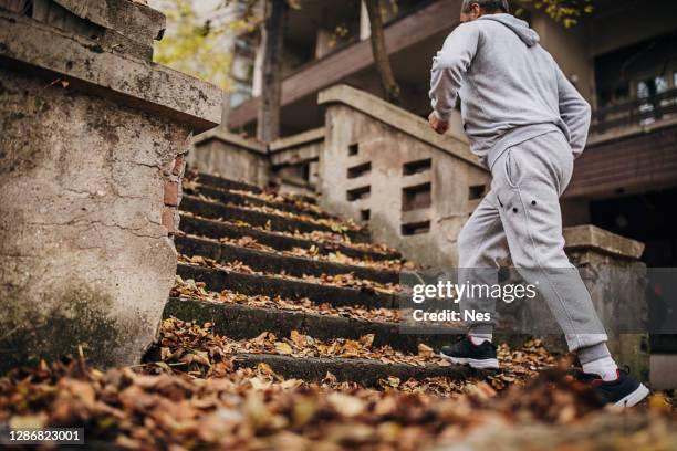 an older man exercises on the steps with autumn leaves - old man feet stock pictures, royalty-free photos & images