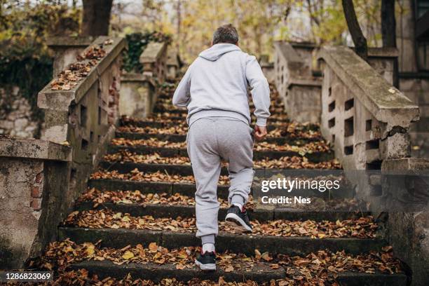 an older man exercises on the steps with autumn leaves - old man feet stock pictures, royalty-free photos & images