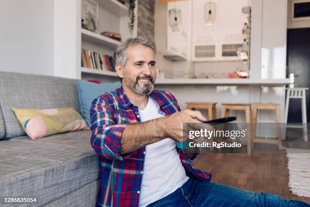 mature man watching tv and enjoying coffee - 50 watching video stock pictures, royalty-free photos & images