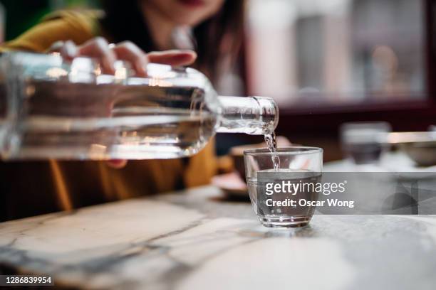 close up shot of woman pouring water into glass at restaurant - fülle stock-fotos und bilder