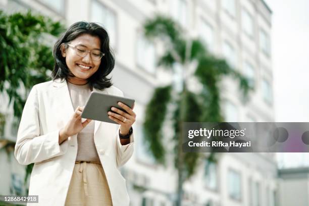 junge asiatische frau analysiert rechtliche daten auf tablet - malaiischer herkunft stock-fotos und bilder