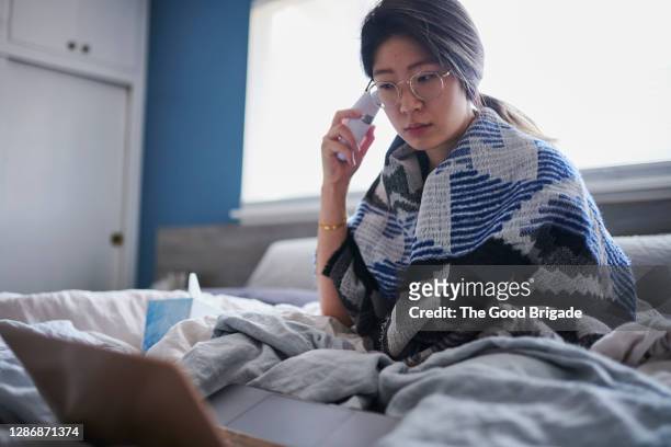 woman taking temperature in bed with digital thermometer - misurare la temperatura foto e immagini stock