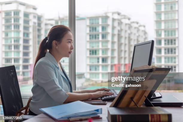 gerichte jonge advocaat die aan computer in bureau werkt - werk in uitvoering stockfoto's en -beelden