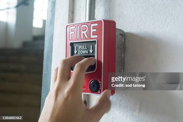 the hand of man is pulling fire alarm on the wall next to the door - brand advocacy stock-fotos und bilder