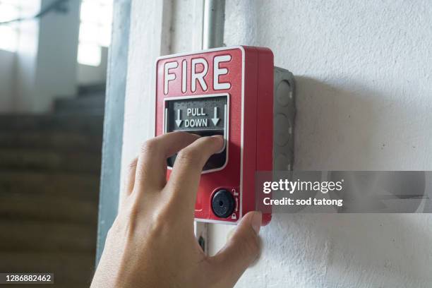 the hand of man is pulling fire alarm on the wall next to the door - workplace evacuation stock pictures, royalty-free photos & images