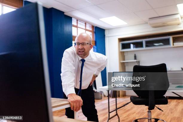 male office employee standing looking at screen squinting to see. - person surrounded by computer screens stock pictures, royalty-free photos & images