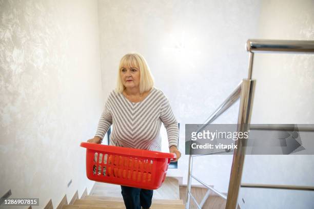 mature woman with laundry basket - carrying laundry stock pictures, royalty-free photos & images