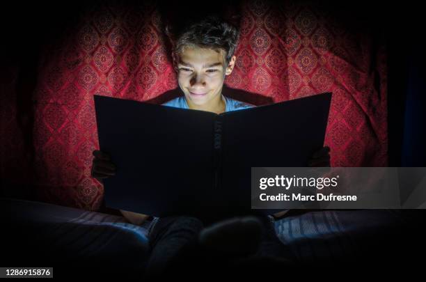 boy reading a magical book - glowing book stock pictures, royalty-free photos & images