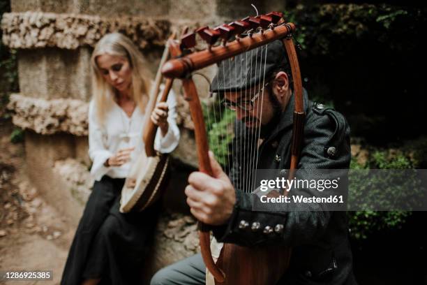 male and female playing lyra instrument in public park - lyre stock pictures, royalty-free photos & images