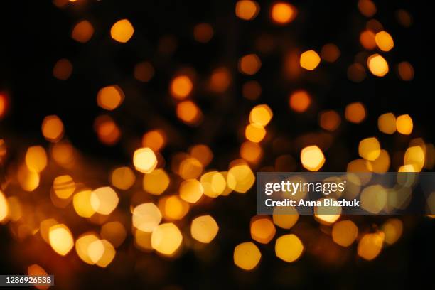 defocused yellow warm golden lights blurred bokeh. festive black christmas or new year background. - flare stockfoto's en -beelden