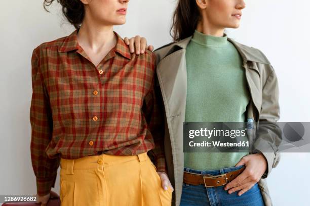 female friends wearing retro style clothing standing against wall - camicetta a quadri foto e immagini stock