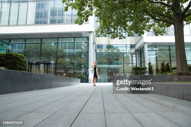 woman walking with shopping clothes at office park - kantoorpark stockfoto's en -beelden