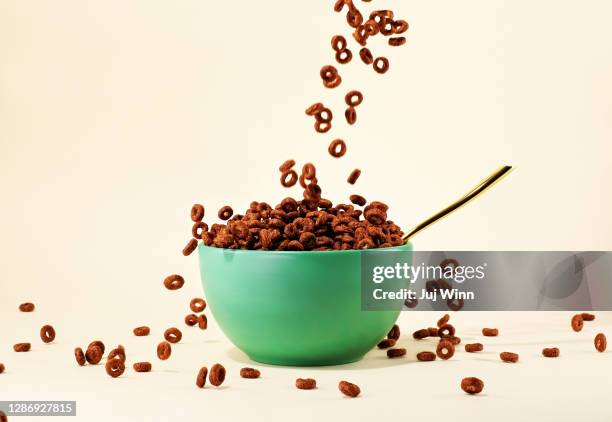 chocolate cereal pouring into green bowl - overlopen stockfoto's en -beelden