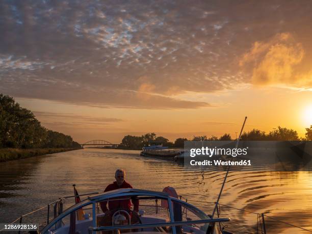 man sailing boat along juliana canal at sunrise - meuse river stock-fotos und bilder