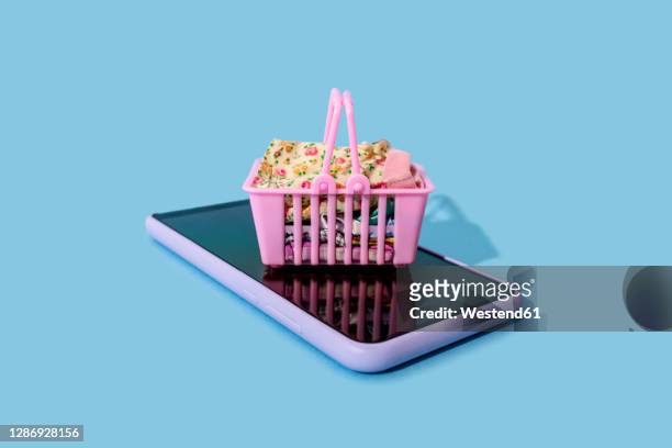 miniature shopping basket lying on top of smart phone - convenience basket stock pictures, royalty-free photos & images